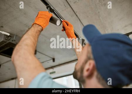 Male hands in gloves repairing ceiling lamp Stock Photo