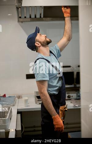 Cheerful male worker checking ceiling in cafe Stock Photo