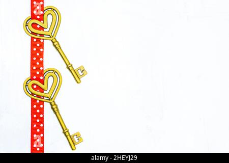 Two romantic style heart shaped skeleton keys on a dotted red ribbon. Romantic background with copy space. Stock Photo