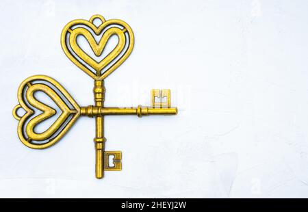 Two vintage style heart shaped skeleton keys crossed on a neutral background with copy space. Stock Photo