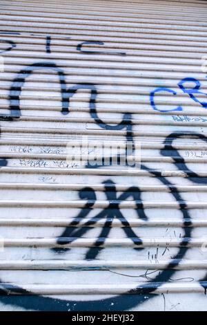 Silver metal garage rolling door with the vandalism and graffiti spray painted Stock Photo