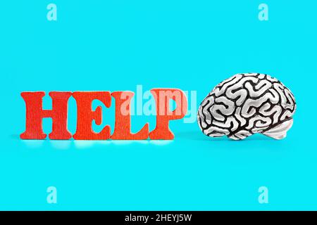 Anatomical copy of a human brain lying by a HELP sign made from red wooden letters. Mental health support concept. Stock Photo