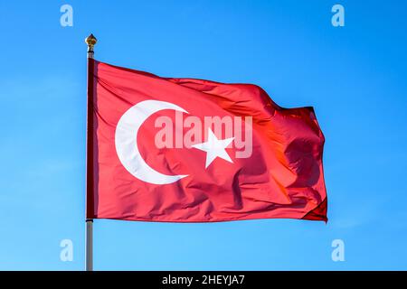 The national flag of Turkey is flying in the wind at full mast against blue sky. Stock Photo