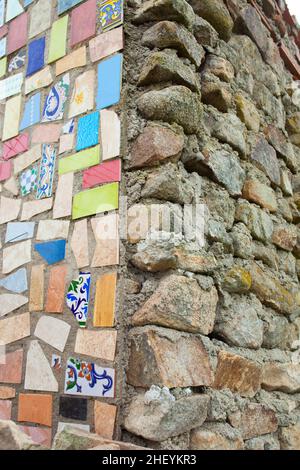 Corner building made part with recycled glazed tiles and half with stones. Recycling construction materials concept Stock Photo