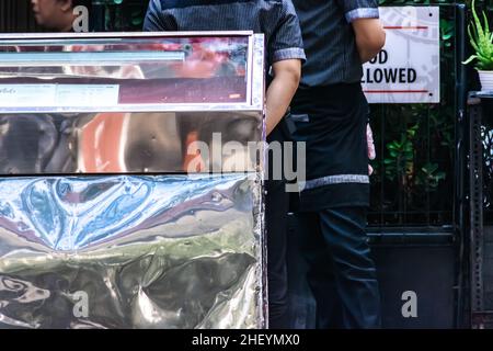 Two waitress with black uniform stands and wait for the guest at the store front on the city sidewalk cafe Stock Photo