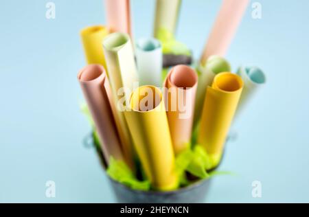 Side shallow depth of field view of pastel color paper rolls in container with copy space. Indoors studio shot. Stock Photo