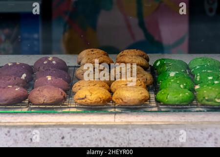 Delicious and tasty baked colorful cookies displayed on the black steel grill mat inside the glass food case Stock Photo