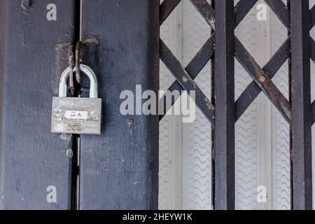Silver metal padlock hanging on the locked black iron entrance Stock Photo