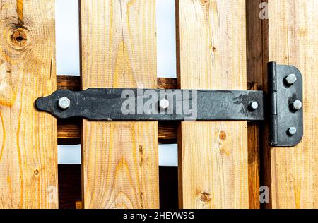 Black metal door hinge screwed to a wooden door Stock Photo
