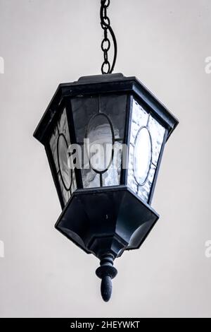 black vintage and classic metal ornament lamp hanging on the white ceiling with low angle view Stock Photo