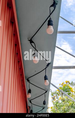 closed store front with pink color boxed rolling door and the string lights hanging on the pastel green walls Stock Photo