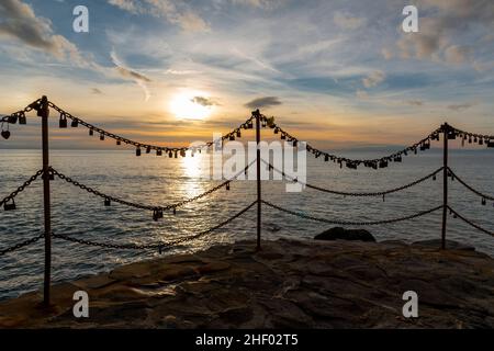 view from the pier at sunset on the sea with silhouette of padlocks closed on chains Stock Photo
