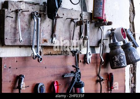 various garage tools for a workshop for auto service and car repair hangs on the wood wall Stock Photo