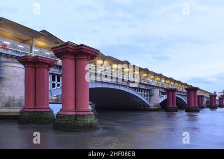 Blackfriars Railway Bridge and remains of the old bridge at dusk in London UK, viewed from the north bank of river Thames. Stock Photo