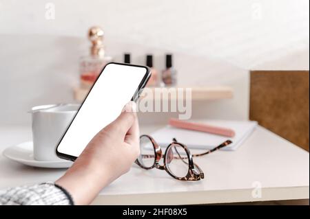 Female hand holding cellphone with white screen. Stock Photo
