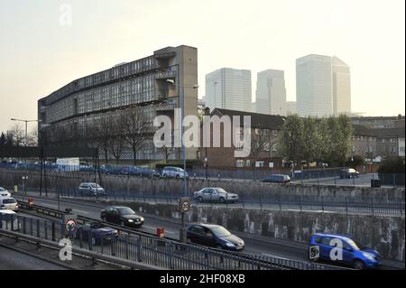 Cars on driveway and Robin Hood Gardens residential development with modern skyscrapers in background, Poplar London UK. Stock Photo