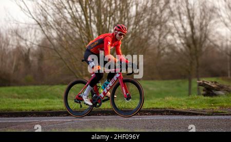 Cyclist wearing skin tight lycra and a cycling helmet on a country road Stock Photo