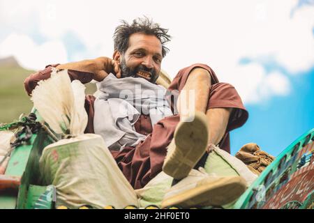 Gilgit, Pakistan - June 08, 2020: Leaning on the Bright Traditional Truck Smiling Man Stock Photo