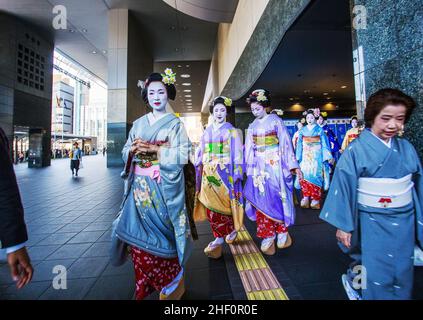 03/28/2015  Kyoto Japan. Maiko - students of  geisha or geishas , young women,  in kimono  walking on wooden geta  next to Kyoto station. Stock Photo