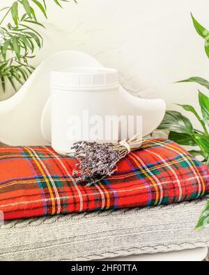 A bottle of detergent for washing woolen things on a stack of knitted blankets with a bouquet of lavender. The concept of housekeeping, cleaning and h Stock Photo