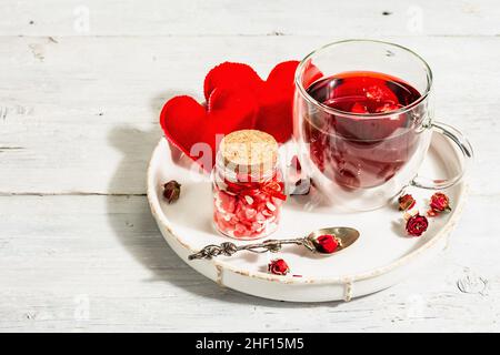 Hibiscus tea. The healthy hot organic drink is served in glass cups. St.Valentine's symbols as hearts, rose petals, and sweet sugar candies. Hard ligh Stock Photo