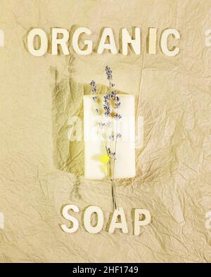 Eco friendly composition with a bar of handmade natural soap with lavender flowers on a crumpled kraft paper background with the inscription organic s Stock Photo