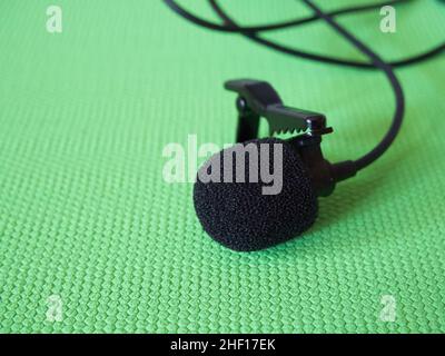 Lavalier microphone on a green background, close-up. A lavalier microphone or lavalier is a small microphone used for television, theater, and public Stock Photo