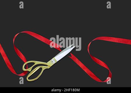 Grand opening, Gold scissors cutting red silk ribbon against black background, Top view, banner, copy space. Stock Photo