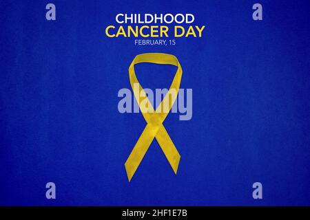 Childhood Cancer Awareness Yellow Ribbon on blue background with copy space. Childhood Cancer Day February, 15 Stock Photo