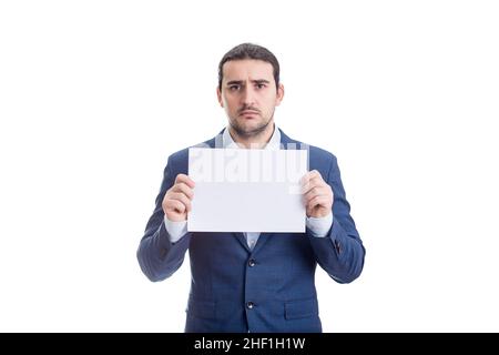 Upset businessman holding a blank paper sheet with copy space, looking sad and disappointed to camera, isolated on white background Stock Photo