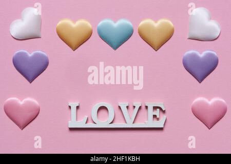 Valentine day background of many different colorful textile hearts on pink soft background. Copy space. Stock Photo