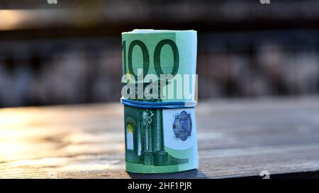Roll of 5000 Euro in 100 Euro banknotes isolated on wood background Stock Photo