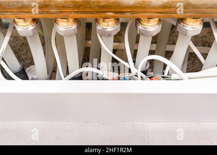 New brass manifold for underfloor heating with plastic pipes and connected electric cables for thermoelectric actuators. Stock Photo