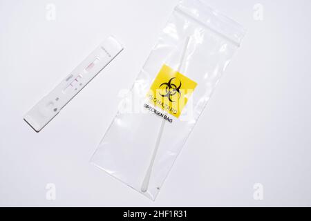 Positive at-home covid self-test with swab in biohazard plastic bag on white background. Over-the-counter OTC tests for corona pandemic Stock Photo