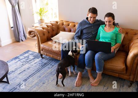 Caucasian couple using laptop sitting together on the couch at home Stock Photo
