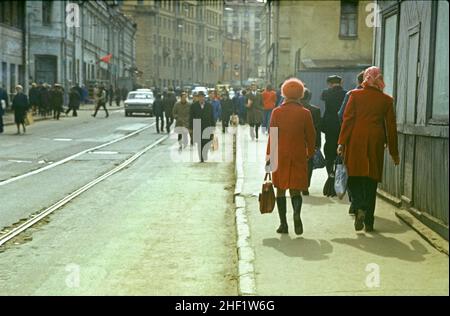 Street scene. Two women in red walk along the sidewalk. Moscow, USSR, May 1976 Stock Photo