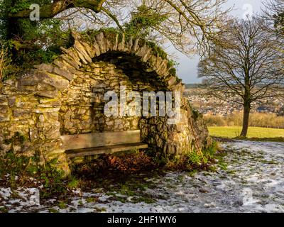 Snow covered landscape with trees at High Tor in Matlock Bath in the Derbyshire Peak District England UK with stone shelter and seat in foreground. Stock Photo