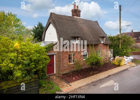 Clare, Suffolk - 27 April 2018: Renovated traditional english thatched cottage with sloping roof and exposed red brick walls on the roadside Stock Photo