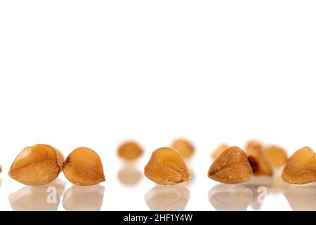 Several grains of uncooked organic buckwheat, macro, isolated on white. Stock Photo