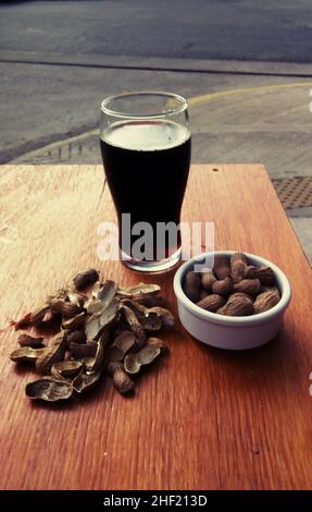 Black craft beer with peanuts on wooden table Stock Photo