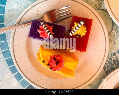 Various colored cakes on plates. Sweet desserts. Photo Stock Photo