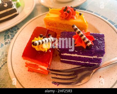 Various colored cakes on plates. Sweet desserts. Photo Stock Photo