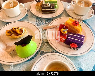 Various colored cakes on plates. Sweet desserts. Photo Stock Photo
