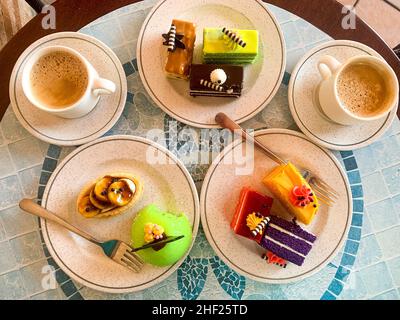 Various colored cakes on plates. Sweet desserts. Photo Stock Photo