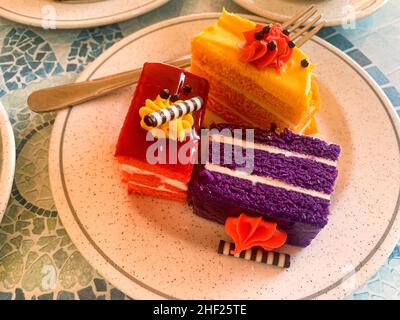 Various colored cakes on plates. Sweet desserts. Photo Stock Photo