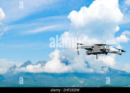 Drone flying overhead in a high cloudy sky with High Tatra mountains on the background Stock Photo