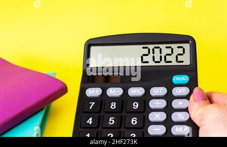 Female hand holds calculator on display number 2022. Business tax. Tax concept of the new 2022. Stock Photo