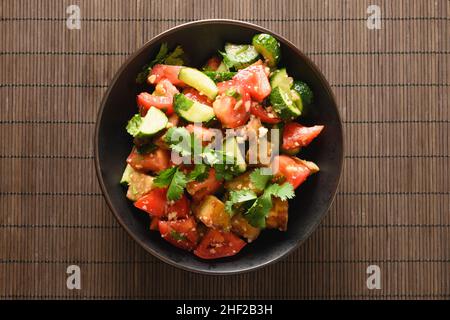 Chinese crispy spicy eggplant with tomatoes, cucumber, garlic, cilantro in oyster sauce and black vinegar isolated on brown mat. Chinese and Asian cui Stock Photo