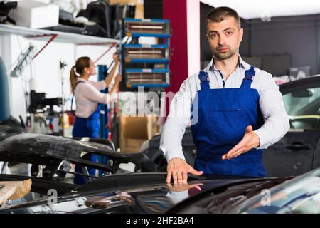 Male worker showing car after repainting Stock Photo