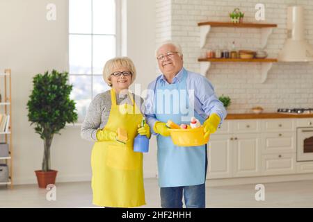 Smiling senior couple standing and looking at camera after cleaning their house together Stock Photo